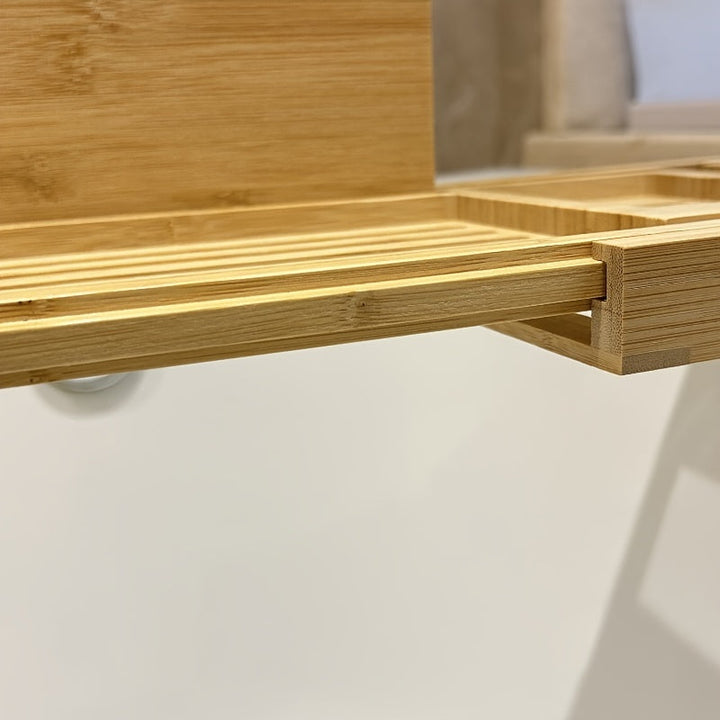 Elegant verstellbare Bambus-Badewannenablage mit Kerze und Getränk, perfekt für entspannende Spa-Momente zu Hause.