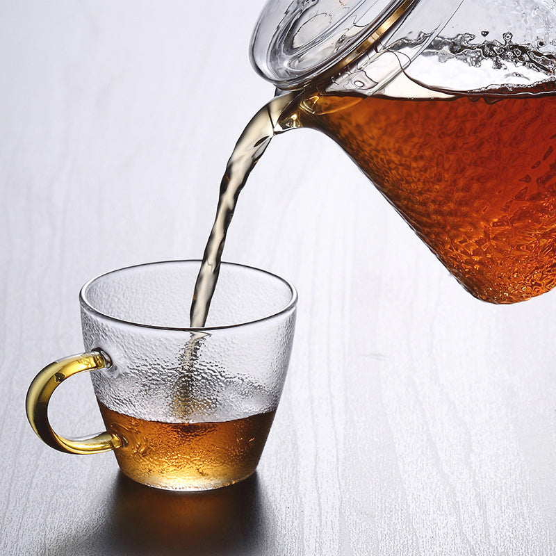 Elegante Teekanne aus gehämmertem, hitzebeständigem Glas mit integriertem Sieb und goldfarbenem Griff. Ideal für Teegenuss.