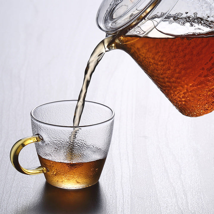 Elegante Teekanne aus gehämmertem, hitzebeständigem Glas mit integriertem Sieb und goldfarbenem Griff. Ideal für Teegenuss.