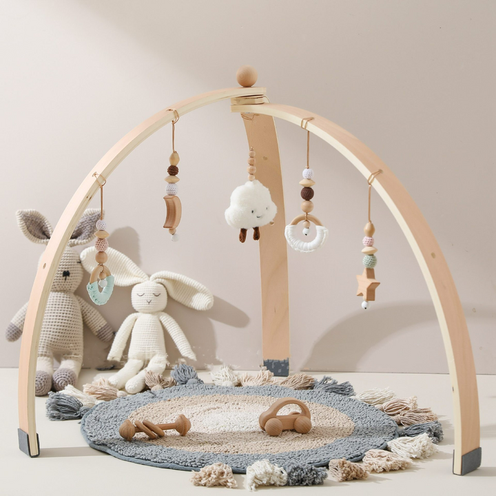 Holz-Aktivitätsbogen für Babys mit bunten Hängespielzeugen zur Förderung von Motorik und sensorischen Fähigkeiten.