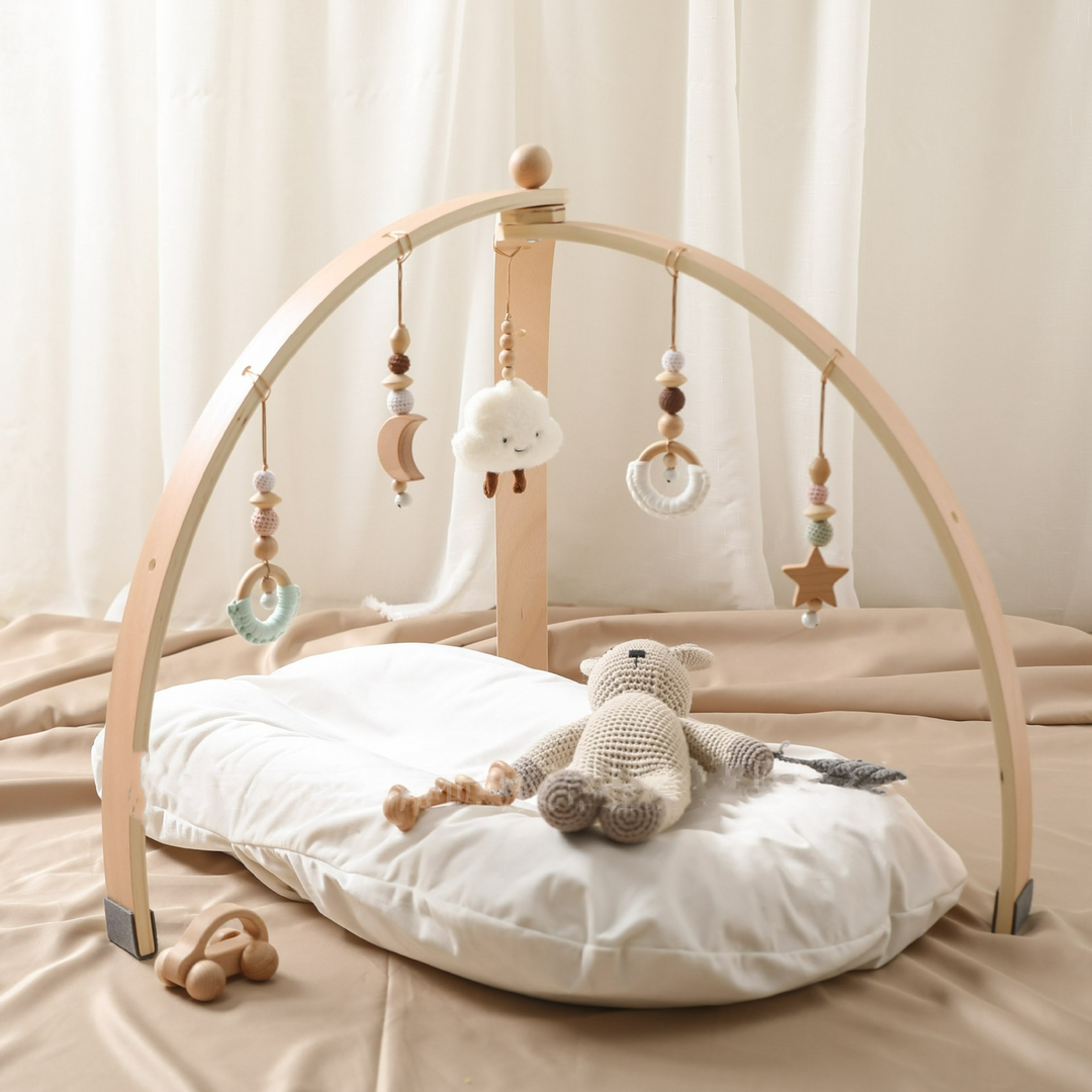 Holz-Aktivitätsbogen für Babys mit bunten Hängespielzeugen zur Förderung von Motorik und sensorischen Fähigkeiten.