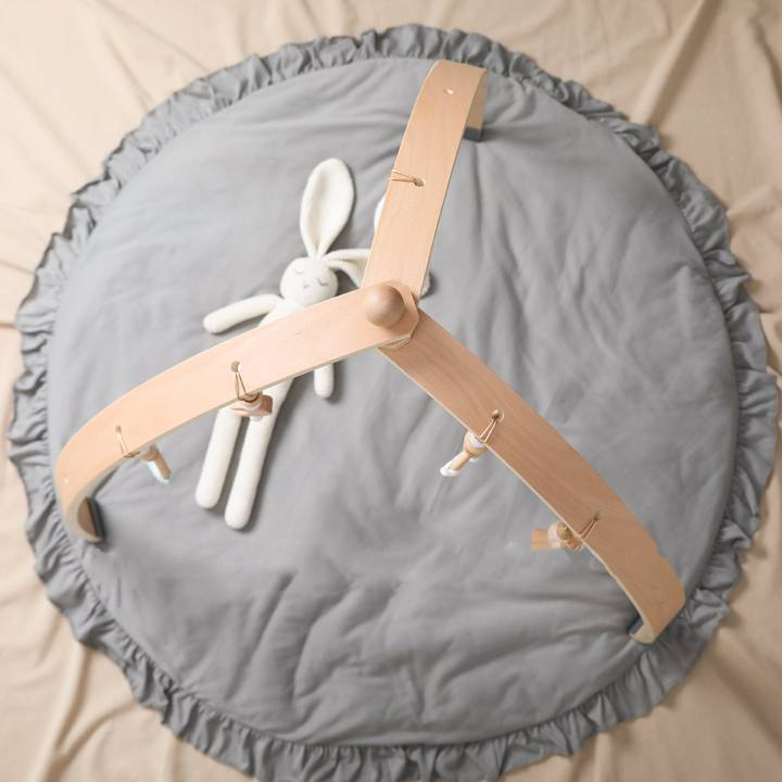 Holz-Aktivitätsbogen für Babys mit bunten Hängespielzeugen zur Förderung von Motorik und sensorischen Fähigkeiten.