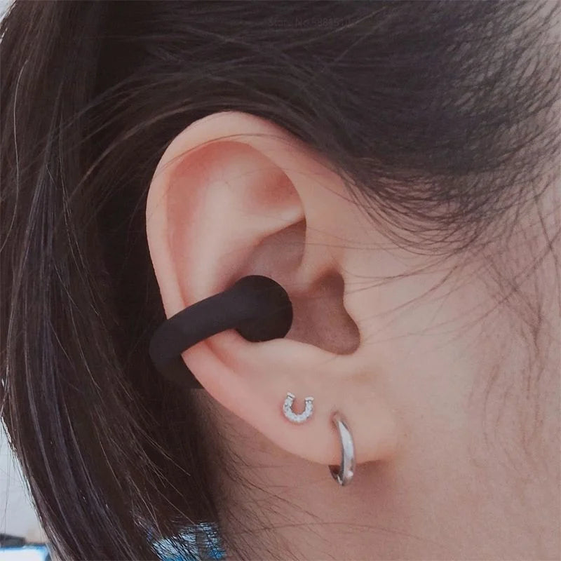 Nahaufnahme einer Frau mit kabellosen schwarzen Knochenschall Ohrhörern, stilvolles Design und kristallklarer HD-Sound.