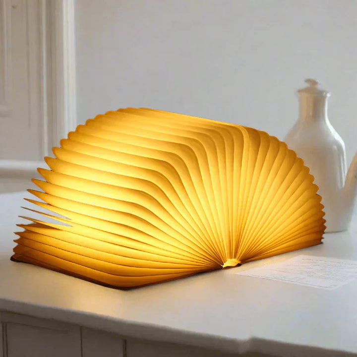 "Zusammenklappbare LED-Buchlampe in Holzoptik, entfaltet wie Märchenbuch, warmes Licht, ideal für Leselampen und Dekoration."